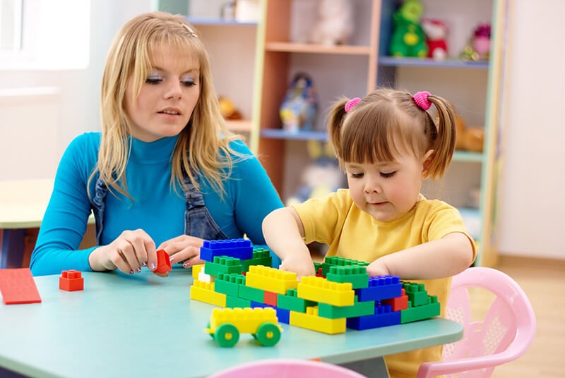 A woman and a child playing with legos.