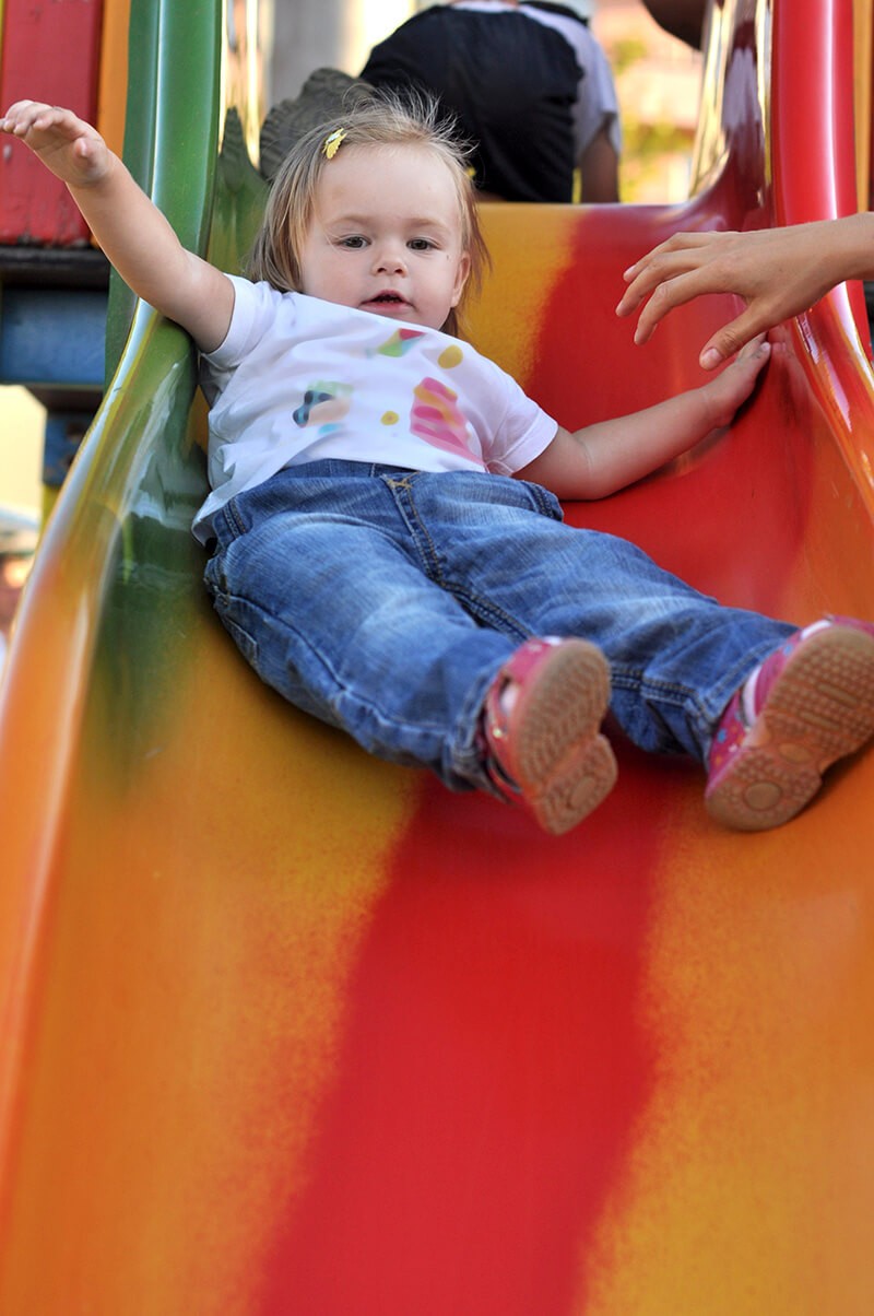 A little girl laying down on a colorful slide.