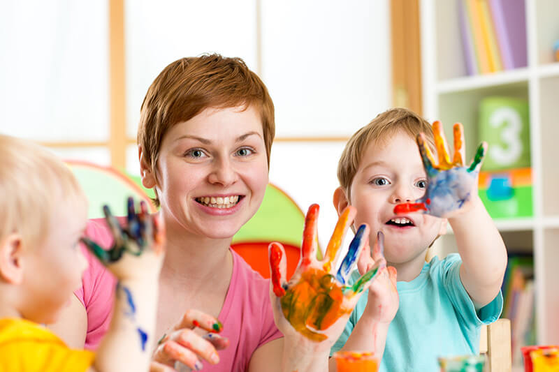 A woman and two children with paint on their hands.