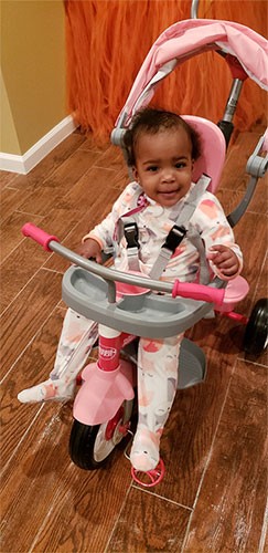 A toddler sitting in a pink color crib